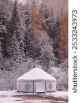 a nomadic yurt in the mountains, against the backdrop of snow-capped mountains and forests, when the first snow fell on the still yellow trees. Kakhastan and Almaty mountains