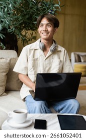 Non binary cute Asian student man sitting in modern coffee shop