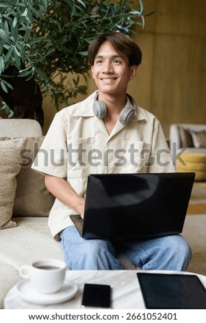 Non binary cute Asian student man sitting in modern coffee shop