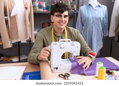 Non binary man tailor smiling confident using sewing machine at atelier