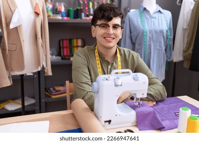 Non binary man tailor smiling confident using sewing machine at atelier