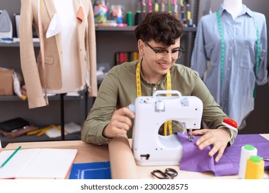 Non binary man tailor smiling confident using sewing machine at atelier