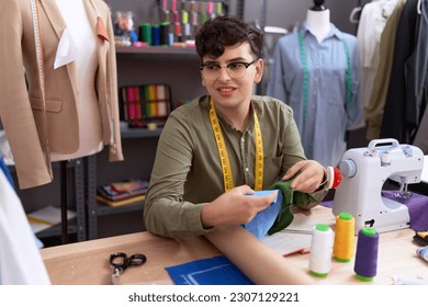 Non binary man tailor smiling confident holding cloths at atelier - Powered by Shutterstock - Get 15% off with code: PIKWIZARD15
