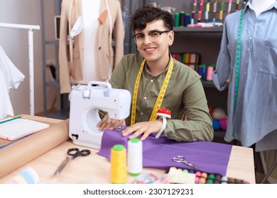 Non binary man tailor smiling confident using sewing machine at atelier