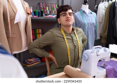 Non binary man tailor stressed using sewing machine at atelier