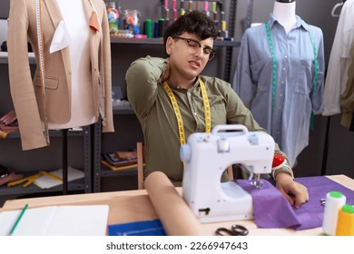 Non binary man tailor stressed using sewing machine at atelier
