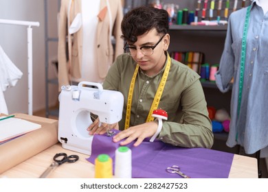 Non binary man tailor using sewing machine at atelier