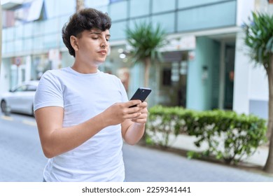 Non binary man using smartphone with relaxed expression at street - Shutterstock ID 2259341441