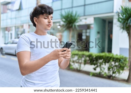Non binary man using smartphone with relaxed expression at street