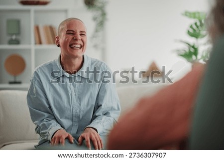 Non binary person finding happiness and support, laughing during a mental health therapy session in a bright, modern room