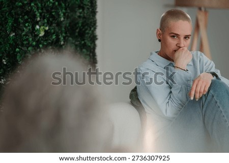 Non binary person with shaved head engaging in active listening, contemplating during a counseling session for mental health support