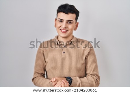 Non binary person standing over isolated background with hands together and crossed fingers smiling relaxed and cheerful. success and optimistic 