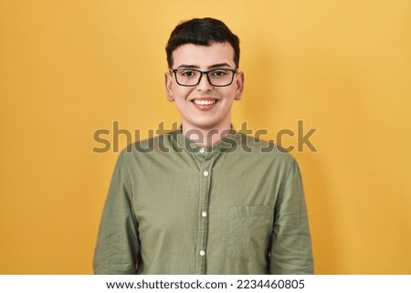 Non binary person standing over yellow background with a happy and cool smile on face. lucky person. 