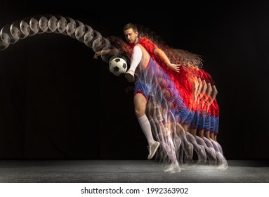 Non Stop Moving. Young Caucasian Football Soccer Player Playing With Ball In Motion In Mixed Light On Dark Background. Concept Of Healthy Lifestyle, Professional Sport, Action, Motion, Hobby, Team.