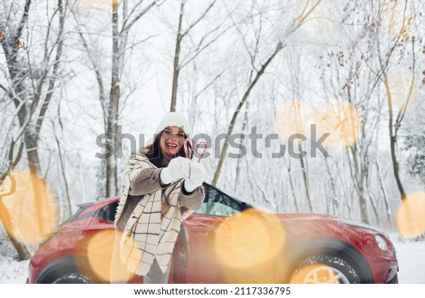 Non urban scene. Beautiful
young woman is outdoors near her red automobile at winter
time.
