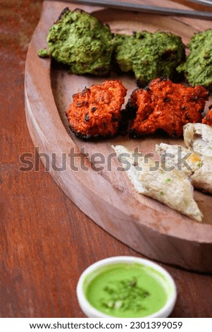 Non veg bbq platter 3 color orange green white serve on wooden tray with side dip chutney Indian restaurant food menu dish close view photography