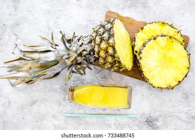 Non-alcoholic beverages. Bottle with fruit juice near pineapples slices on grey background top view