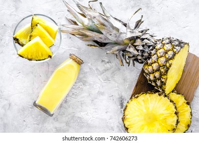 Non-alcoholic beverages. Bottle with fruit juice near pineapples slices on grey background top view