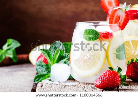 Non-alcoholic cocktail with strawberries, mint, lemon, soda and ice, old wooden background, selective focus