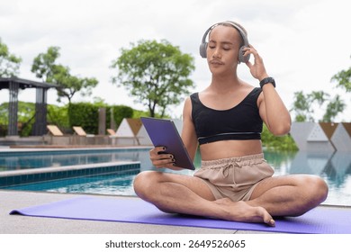 Non-binary Asian person exercising in poolside doing yoga and wearing sport bra
