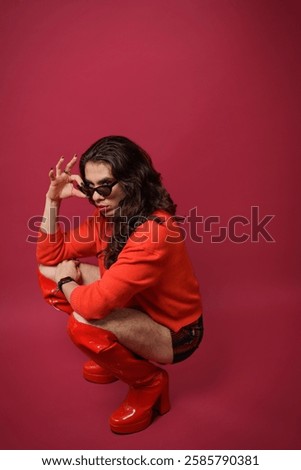 non-binary person is posing on a red studio background Man has an artistic expression. Concept of non-binary people. pride
