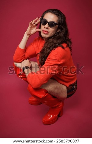 non-binary person is posing on a red studio background Man has an artistic expression. Concept of non-binary people. pride