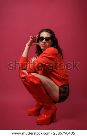 non-binary person is posing on a red studio background Man has an artistic expression. Concept of non-binary people. pride