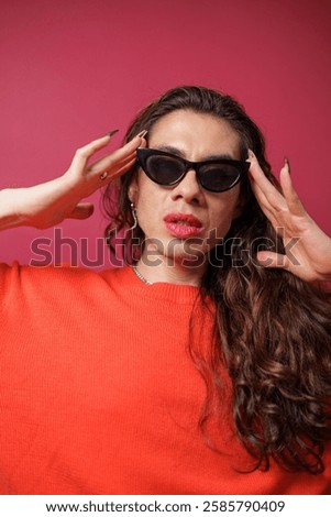 non-binary person is posing on a red studio background Man has an artistic expression. Concept of non-binary people. pride