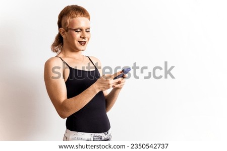 A non-binary person is posing on a white background while using a mobile phone. Chat on dating app. Meeting people of the same sex. Meet people online without leaving home. Copyspace for advertising.