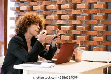 non-binary person purses their lips while applying makeup