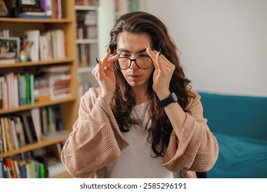Non-binary person putting on glasses to start working from their home library