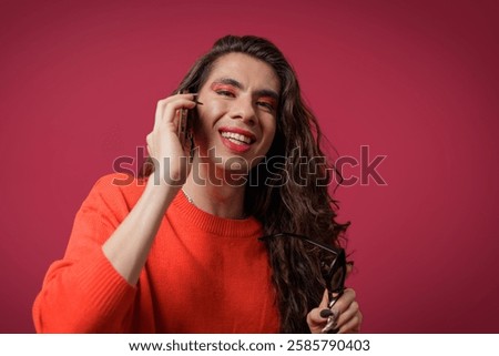 Non-binary person talking on cell phone with a happy expression on their face