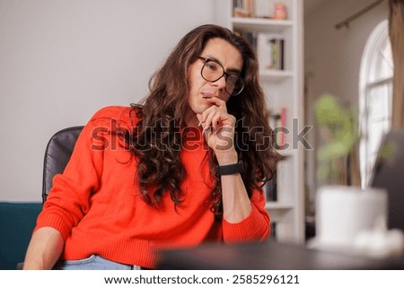 Non-binary person working from home with their laptop with a thoughtful face