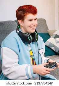 Non-binary smiling person playing video games in the living room at home
