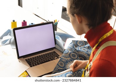 Non-binary transgender woman fashion designer looking at the laptop screen with copy space. Concept of gender fluidity - Powered by Shutterstock