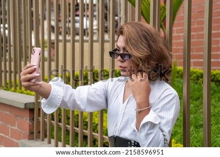 non-binary vain man taking selfie leaning on black gate in the street. Horizontal high quality photo with copy space