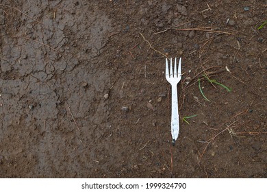 non-biodegradable plastic fork in the ground, pollution