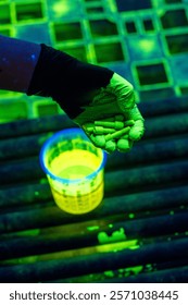 Non-destructive Testing Using Fluorescent Penetrant Method on Industrial Fasteners. Inspector holds illuminated bolts during penetrant testing procedure for crack detection