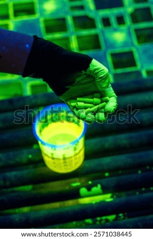 Non-destructive Testing Using Fluorescent Penetrant Method on Industrial Fasteners. Inspector holds illuminated bolts during penetrant testing procedure for crack detection