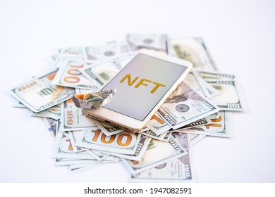 Non-fungible token NFT, crypto art, digital art, new type of cryptorurrency. Cell phone with golden NFT text in golden frame as art object on dollars background