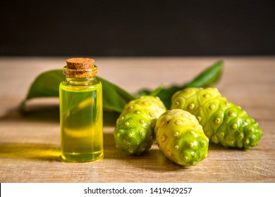 Noni Extract In A Small Bottle And Noni On The Wooden Board.