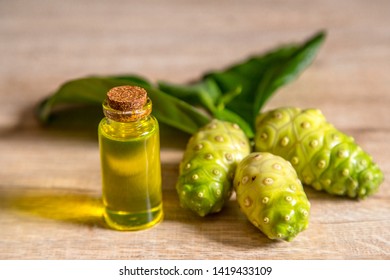 Noni Extract In A Small Bottle And Noni On The Wooden Board.