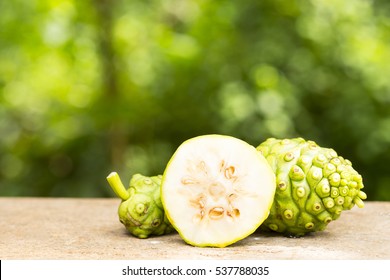 Noni fruit and noni slice on wooden table and green background.Fruit for health and herb for health.01