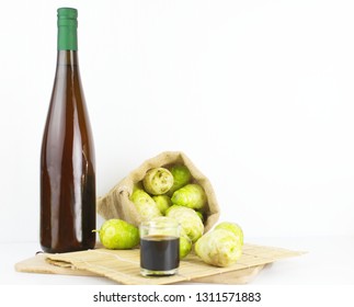 Noni Juice Bottle With Noni Fruit In Sack On Bamboo Mat Isolated Background..jpg