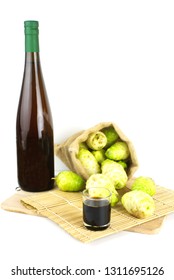 Noni Juice Bottle With Noni Fruit In Sack On Bamboo Mat Isolated Background.