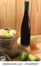 Noni Juice Bottle With Noni Fruit In Sack On Bamboo Mat.Morinda Juice.