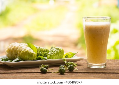 Noni and noni juice on wooden background.Juice for health or fruit for health or herb for health.Outdoor view