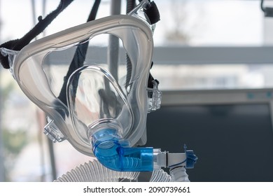 Non-invasive ventilation face mask, close up view, on background medical ventilator in ICU in hospital.