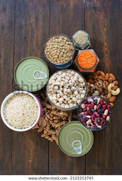 Non-perishable food, canned goods frame.\
Pasta, lentils,rice,nuts,quinoa,beans, chickpea and canned foods on\
a wooden\
background