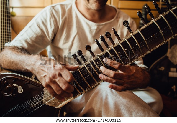 Non-recognisable musician playing sitar,\
traditional indian musical instrument, close up photo of hands.\
Indian folk music\
concept.
